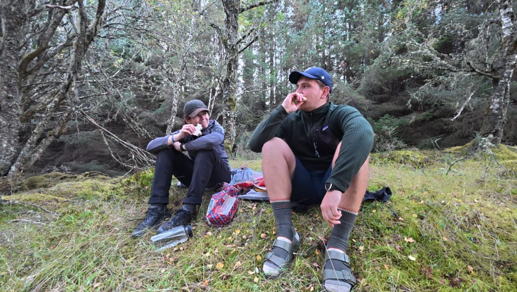 Maresa und Nick sitzen auf einem Hügel und essen eine Pause während ihrer JOGLE‑Fernwanderung durch Schottland