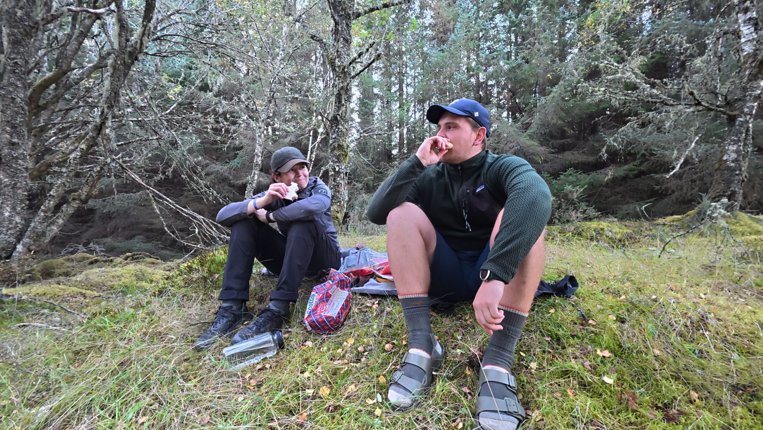 Maresa und Nick sitzen auf einem Hügel und essen eine Pause während ihrer JOGLE‑Fernwanderung durch Schottland