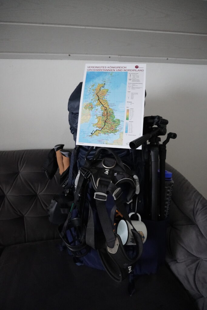 Gepackter Wanderrucksack auf einer Couch mit Karte von Großbritannien, auf der die JOGLE-Route von John o’Groats nach Land’s End eingezeichnet ist