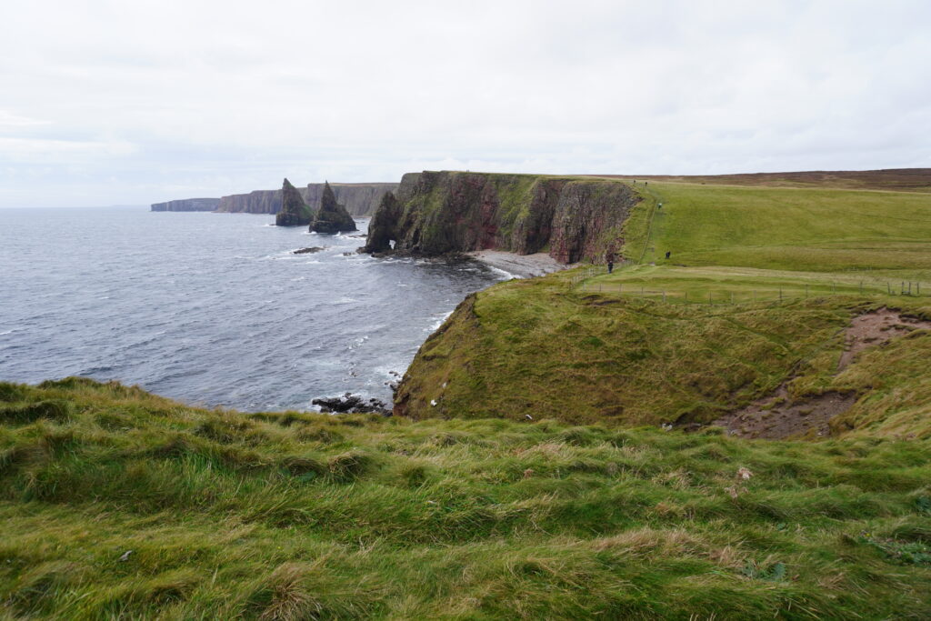 Küstenlandschaft auf dem John o’Groats Trail mit steilen Klippen und Wanderern