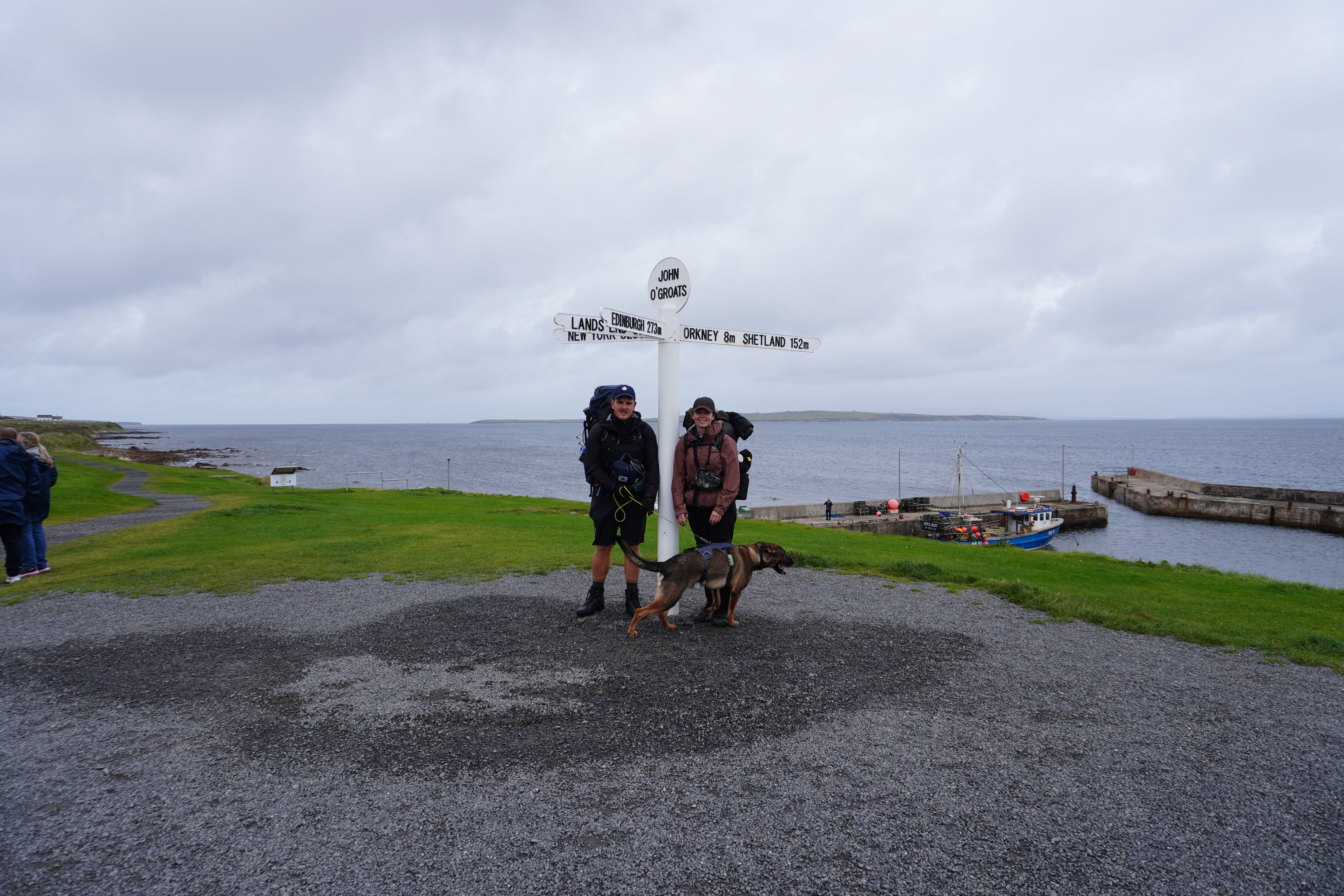 Start des JOGLE in John o’Groats mit Rucksäcken und Hund am nördlichsten Punkt Großbritanniens