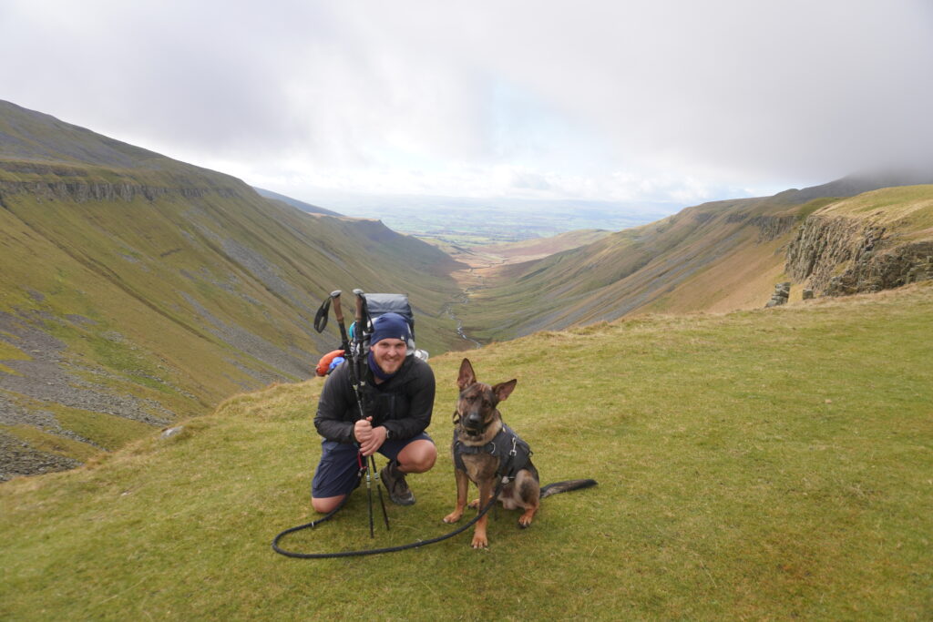 Nick und Nero lachend in die Kamer mit Aussicht auf das Gletschertal High Cup Nick auf dem Pennine Way im Hintergrund