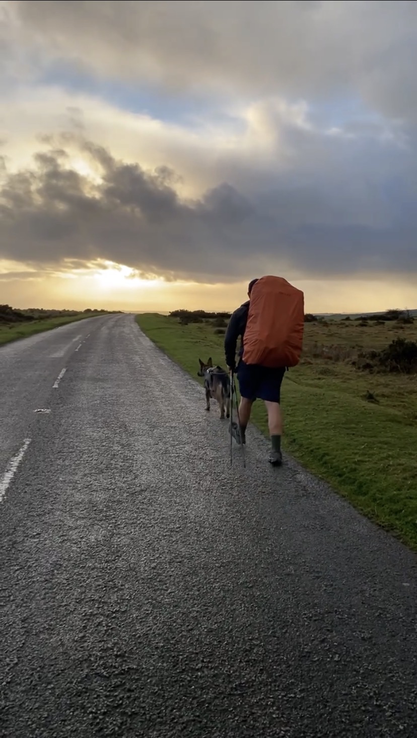 Nick und Nero wie sie gemeinsam auf einer Straße im Sonnenuntergang während der JOGLE Fernwanderung laufen