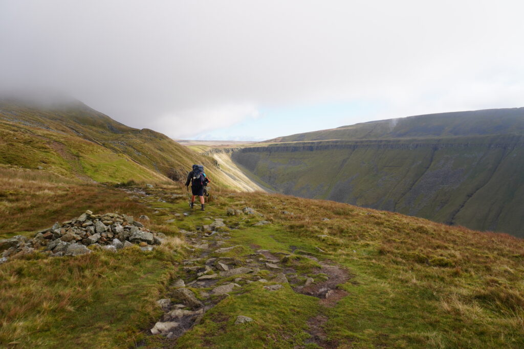 Nick und Nero von der Ferne wandernd durch das Tal High Cup Nick auf dem Pennine Way
