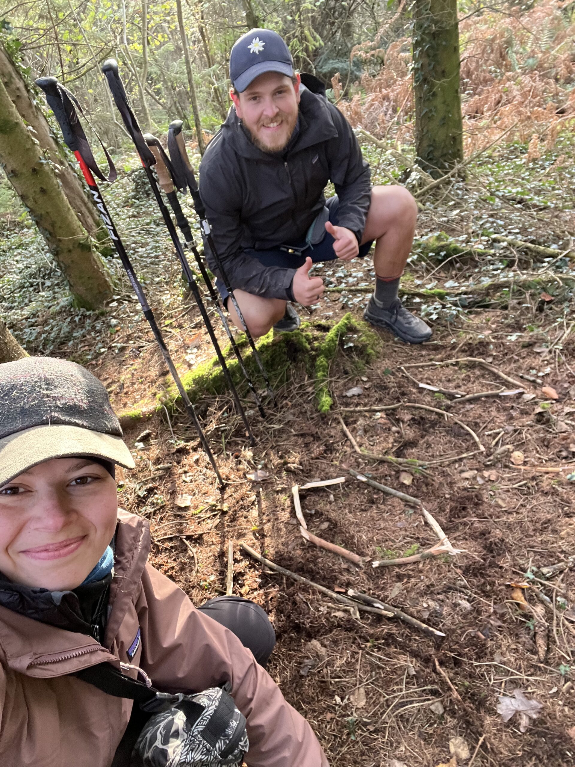 Nick und Maresa in die Kamera lachend vor einer “1000” mit Holzsteckend formierter Zahl während der JOGLE Fernwanderung nach 1000 gelaufenen Kilometern